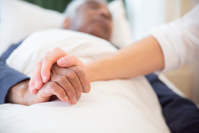 resident-in-bed-holding-someones-hand