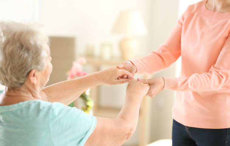 older person being helped up by a woman