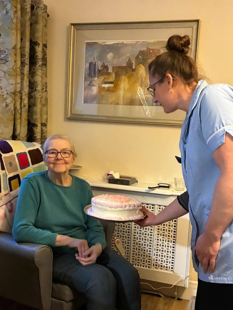 resident with birthday cake and care worker