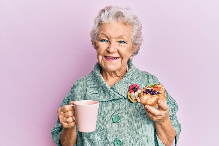 older woman enjoying a cup of tea and a cake