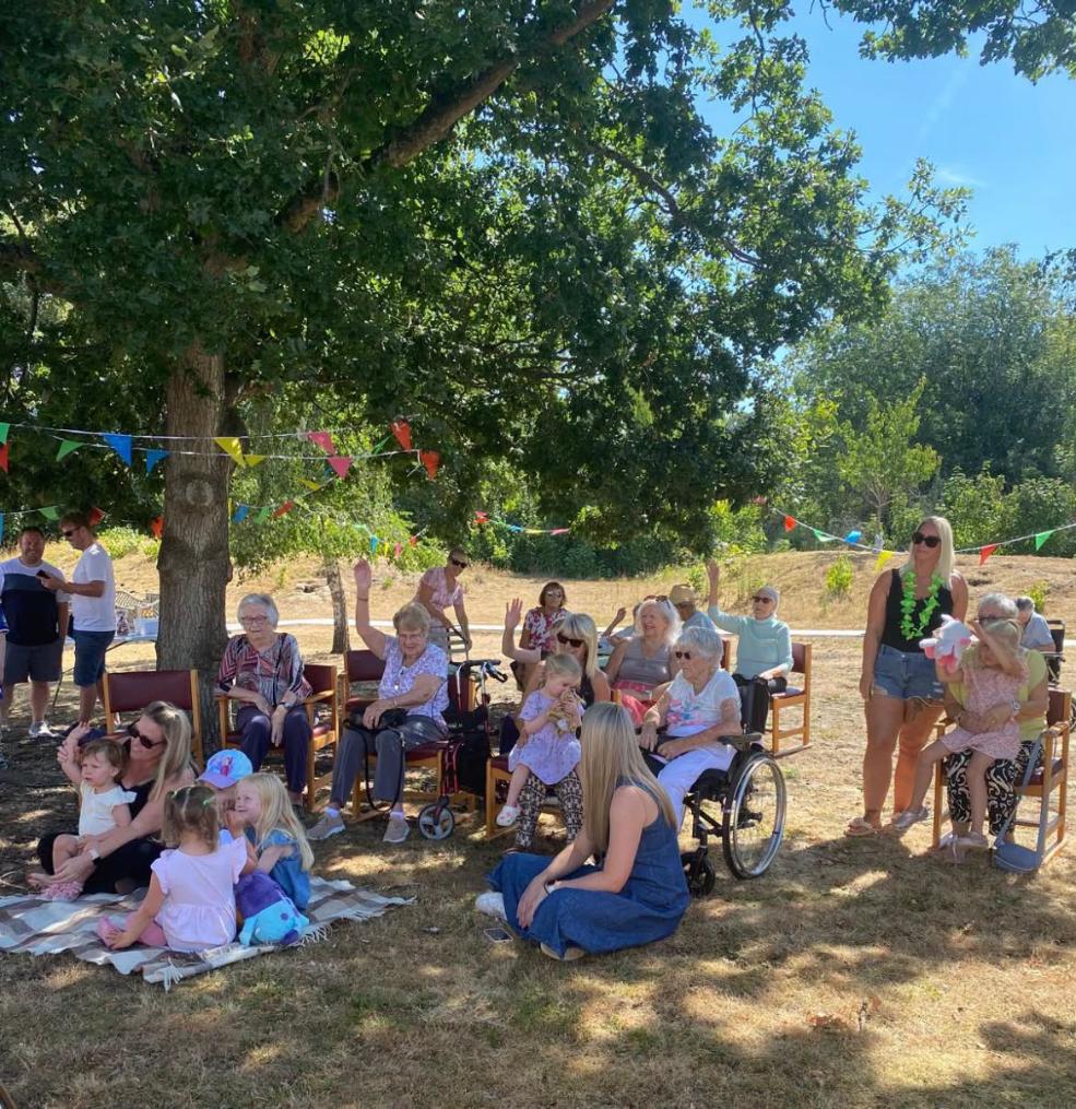 residents and family members sitting under a tree in the garden